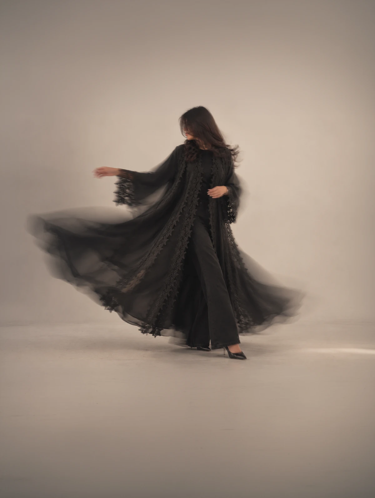 Kohl in black, lace at the sleeves and hem, spinning out as she turns.
