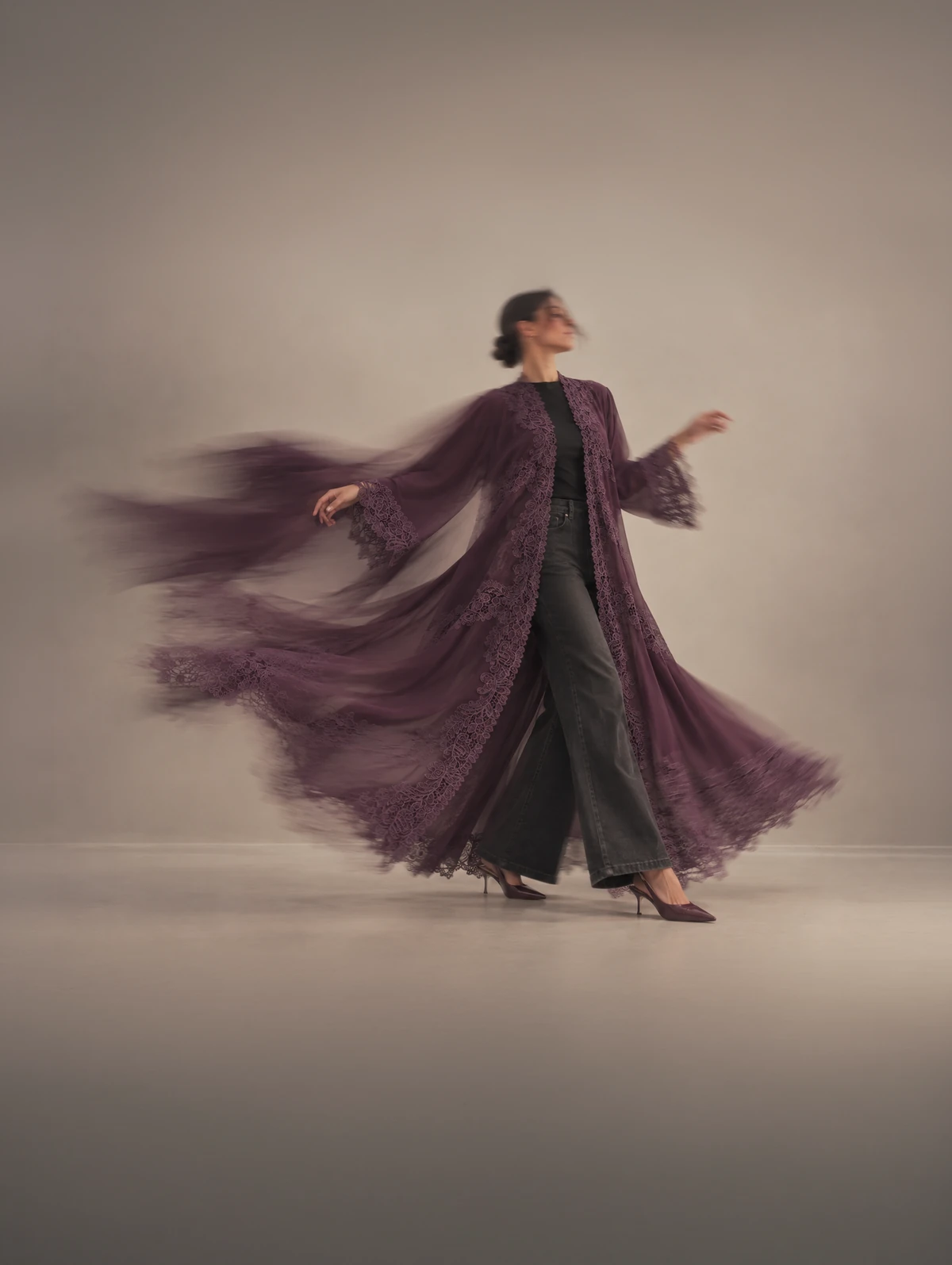 Layali in deep aubergine, the coat flying open over dark trousers.